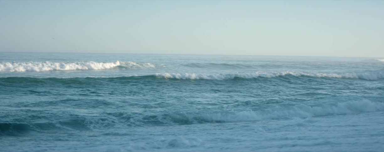 Ocean waves wash onto a beach on a sunny day