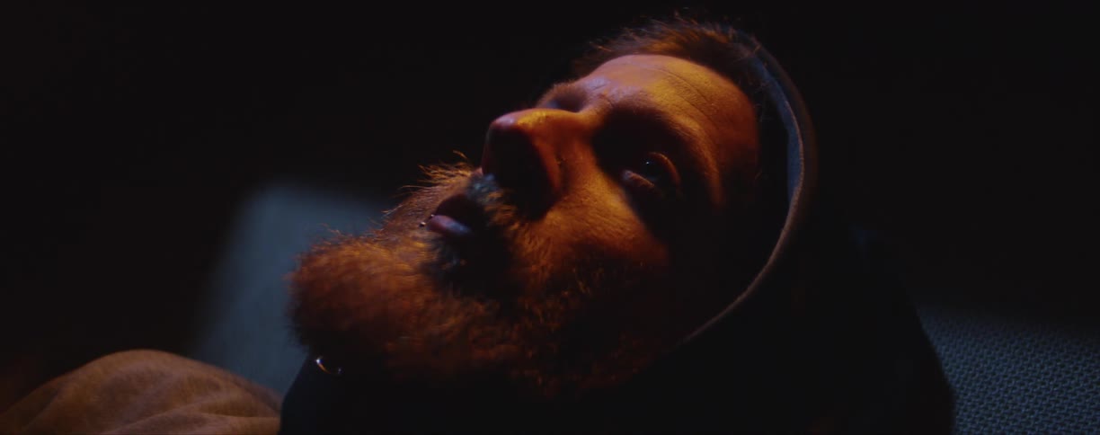 A man lies down and looks above him as a light passes over his face
