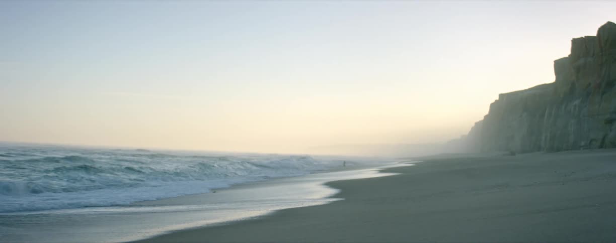 Ocean waves crash against the beach at dawn