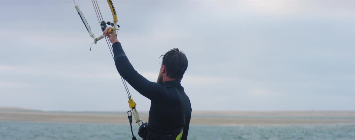 A man in the water holds on to ropes as he waits to get towed