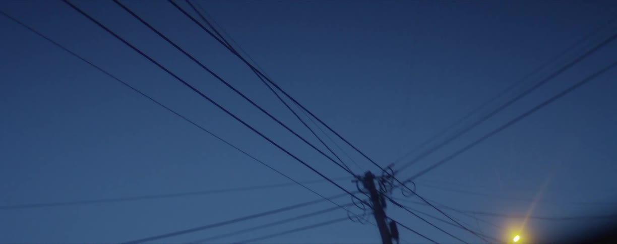 Power lines and street lights viewed while driving down a neighborhood street around sunrisesunset