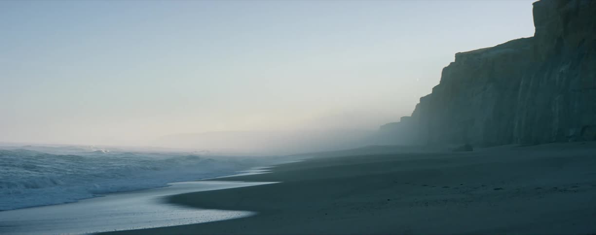 Mist over the beach near the cliffs next to the ocean at evening