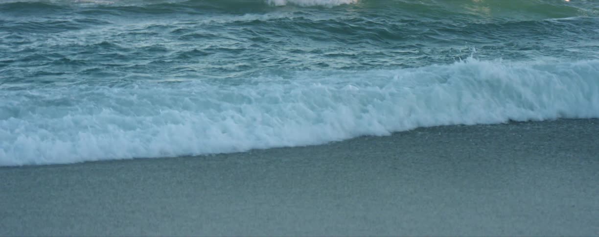 Ocean waves roll into a beach during the day