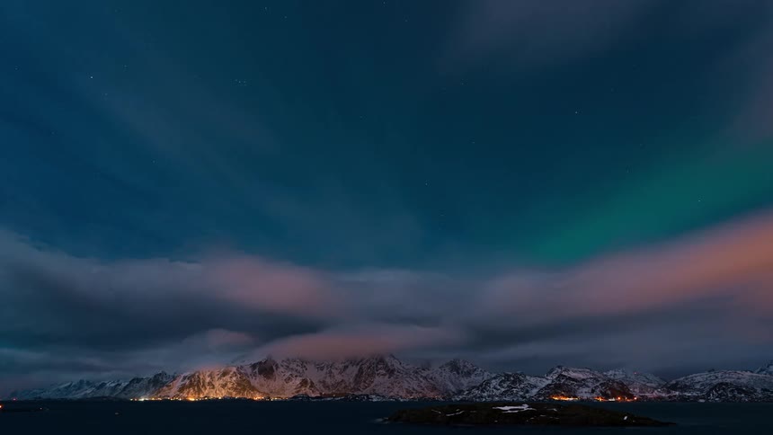 Time lapse of green aurora polar lights in the sky at night over the mountains