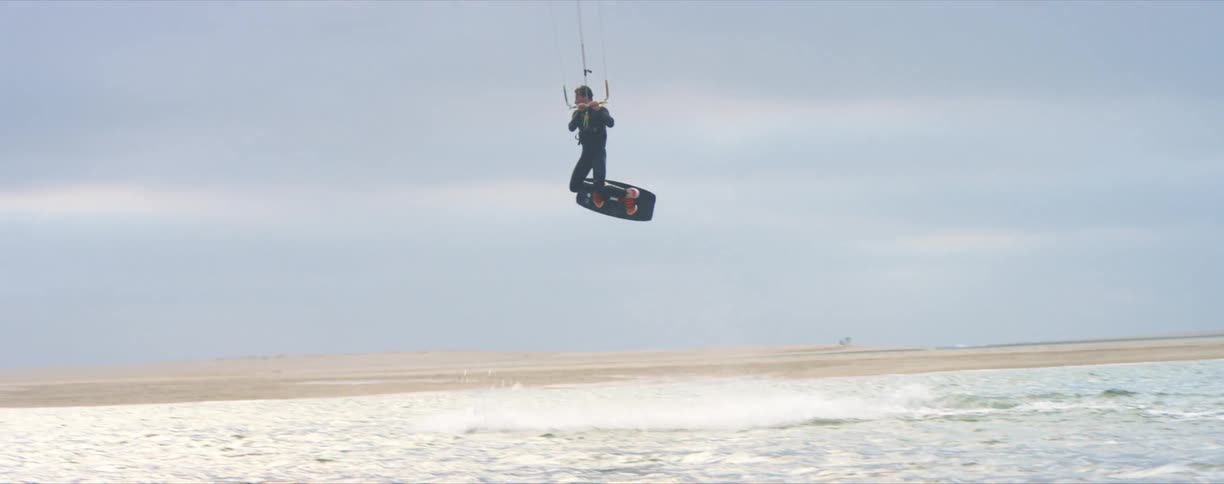 Man kite surfing on the sea water next to the coast at day time