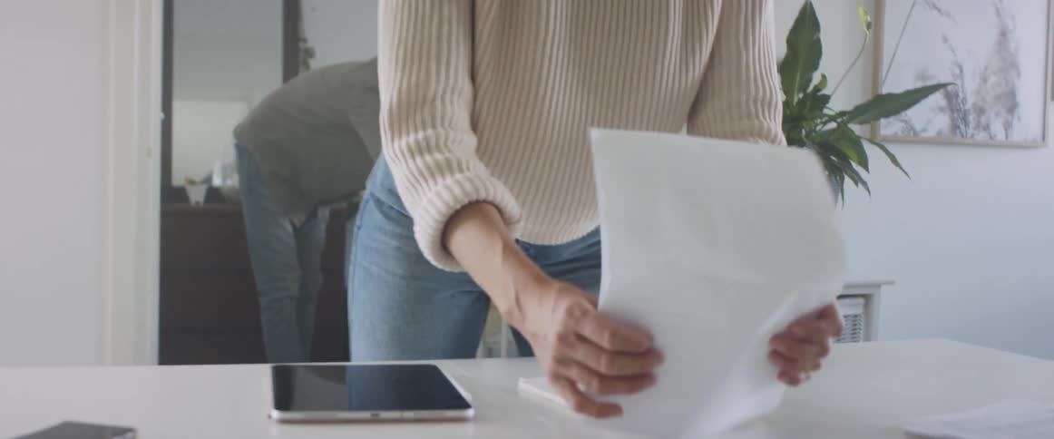 A middle aged woman arranges papers on an office desk