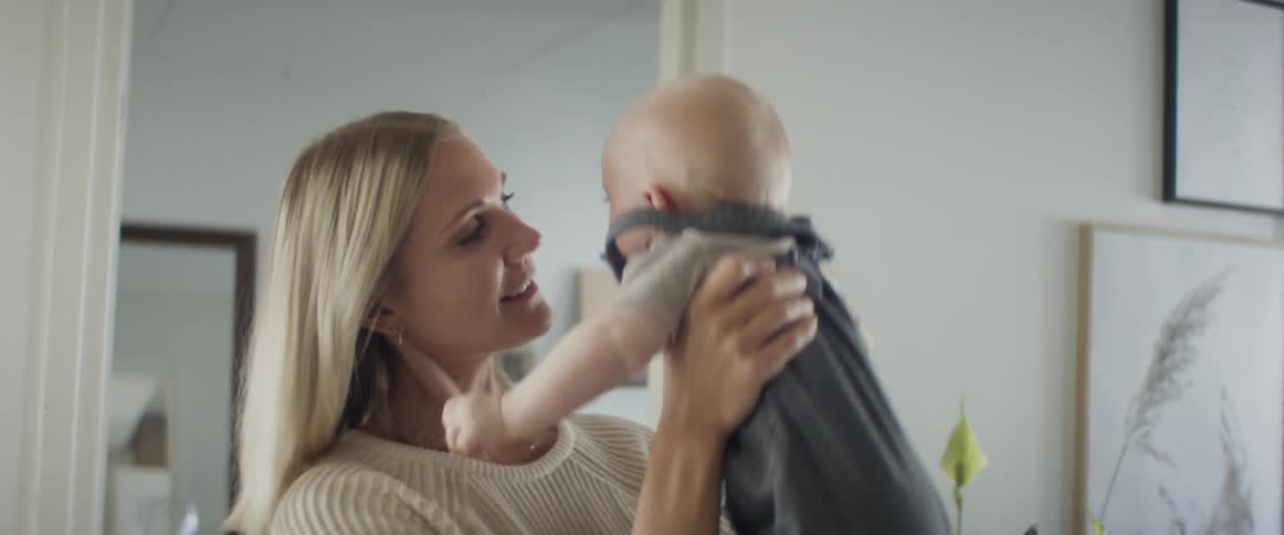 A woman bounces a baby in the air and then holds the baby close to her body