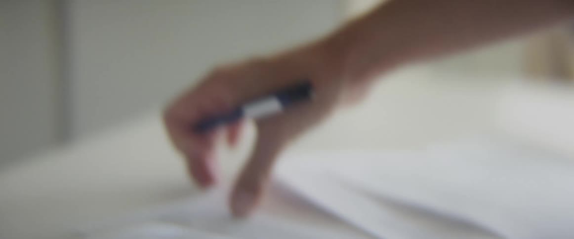 Woman makes notes on printouts and notebook laying on white table near tablet