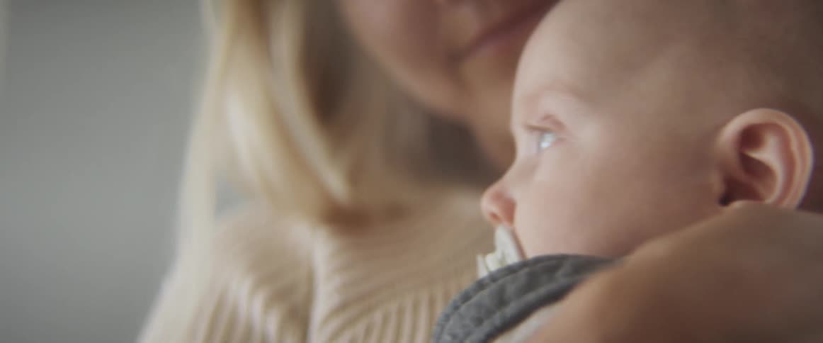 A woman holds her baby and rocks him and kisses him on the head