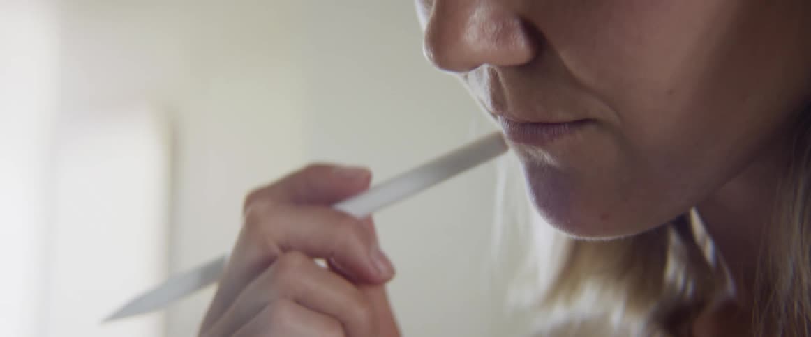 Woman taps pen against face as she thinks