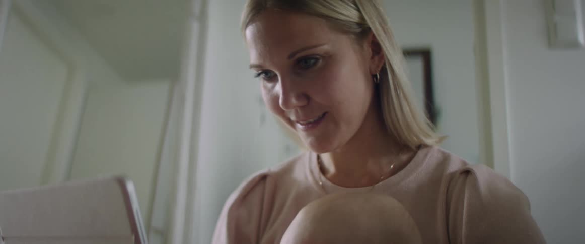 A woman holds an upset baby with a tablet