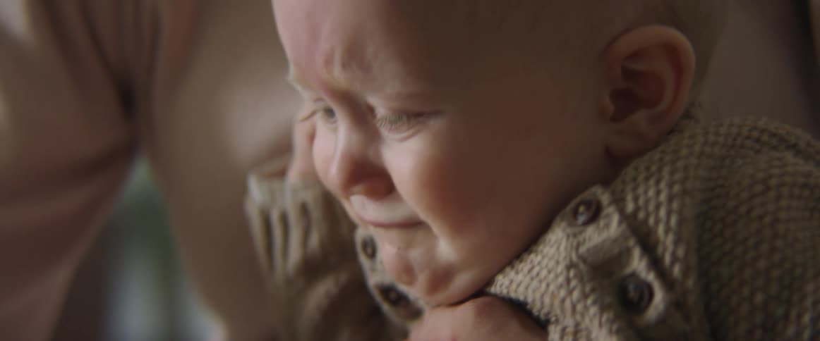A mother tries to comfort her baby son as he cries in her lap