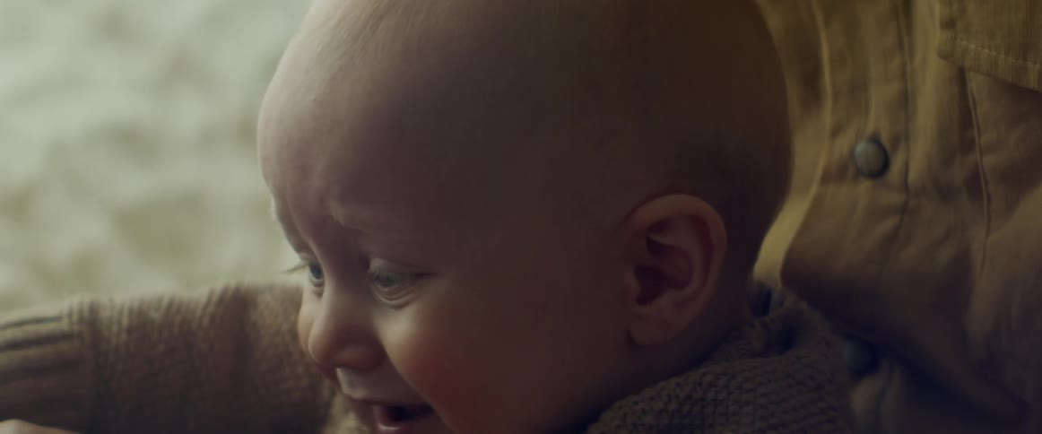 A mother holds her baby as he fusses and then chews on a toy