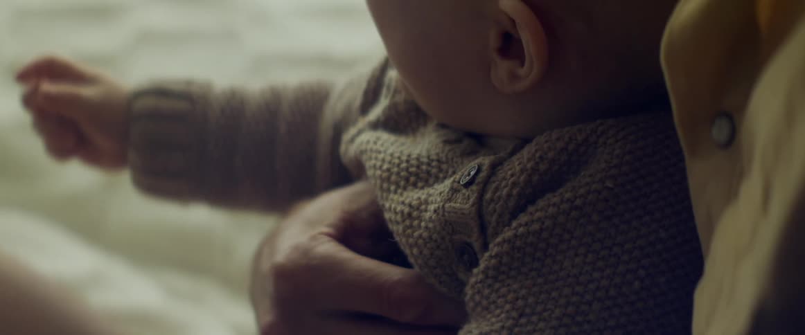 Baby on his father arms sitting in a bed at home