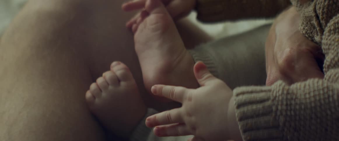 Man cuddles baby as baby plays with his bare toes