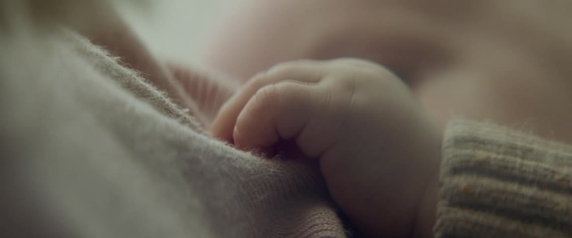 Close up of a babys hand grabbing the mothers clothes