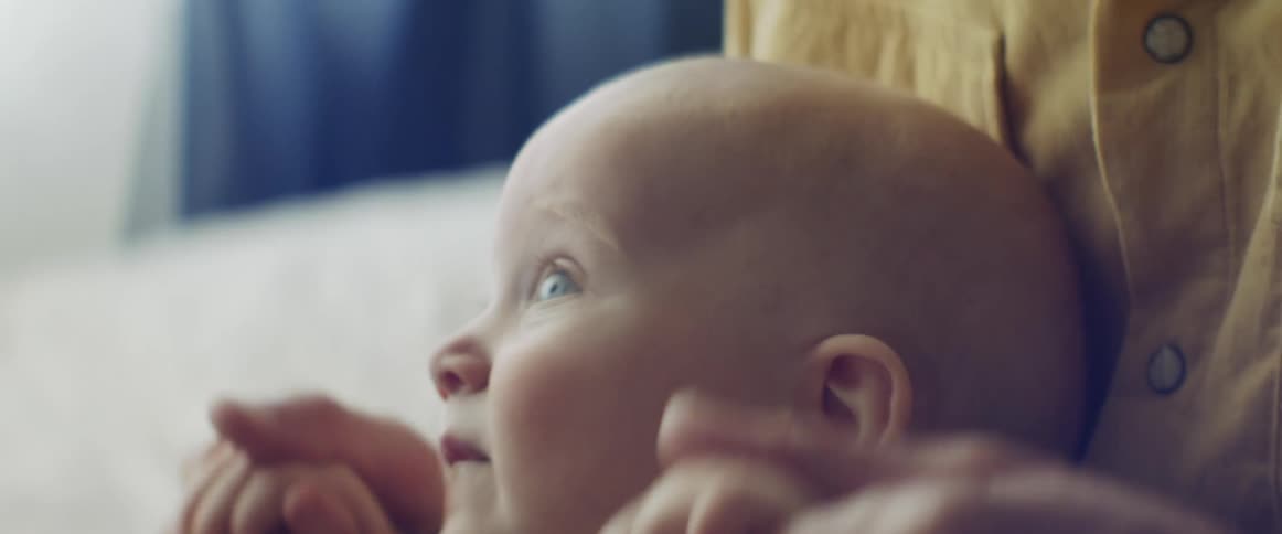 Mother plays with her blue eyed baby on the couch at home