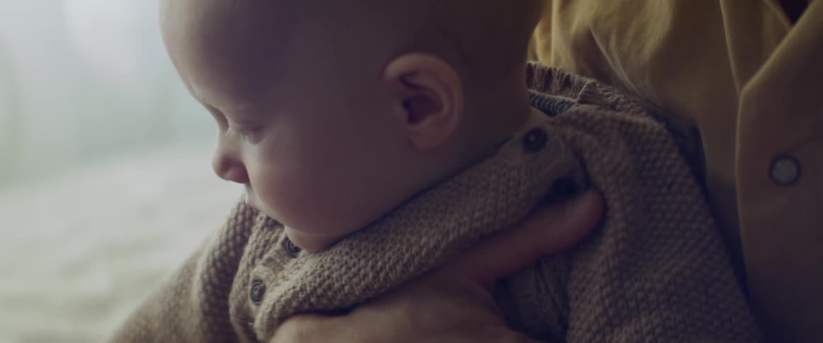 Woman with a yellow shirt holds her baby son