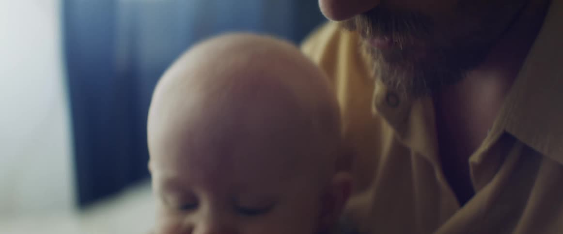 A man holds a baby in his lap as she sits indoors during the day