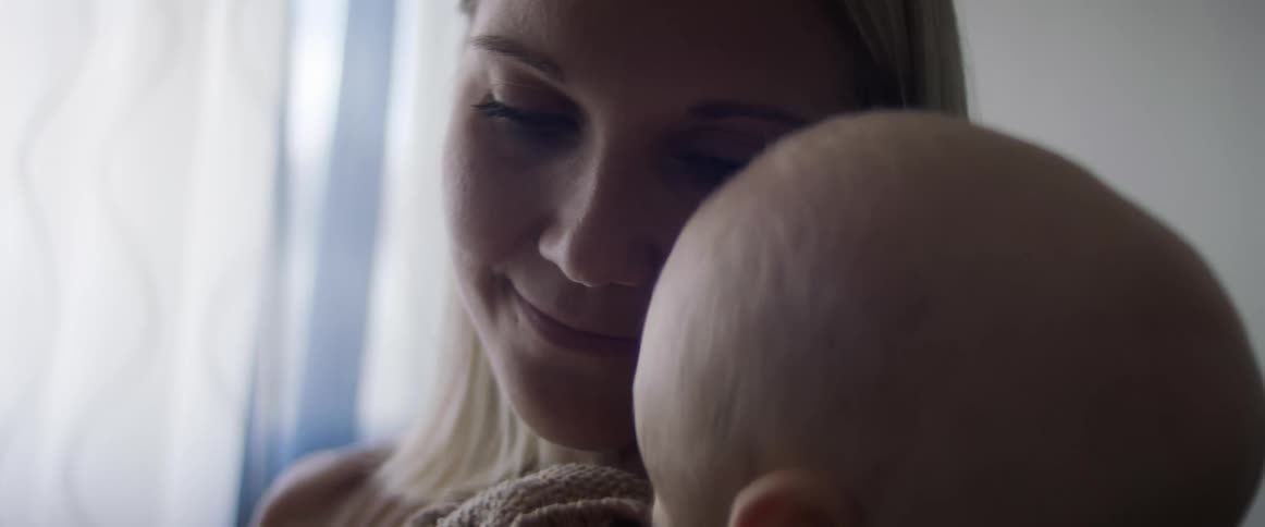 A woman holds her son and smiles as she leans down to rest her head on his head