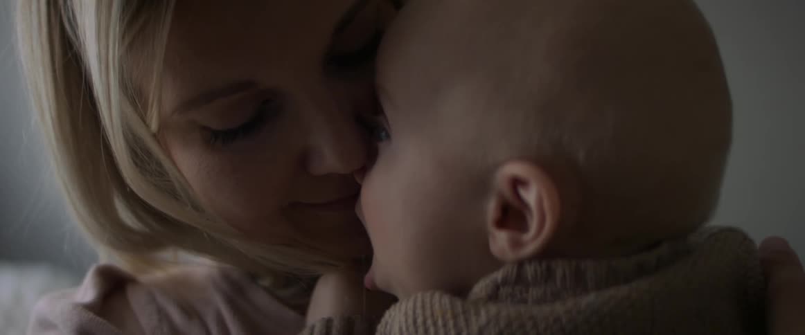 Mother lovingly cuddles with her baby on the couch at home
