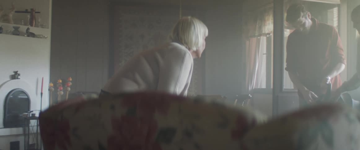 A man and woman show their baby to an older woman in her living room during the day