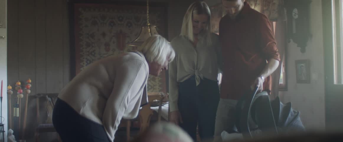 A couple with a baby showing their baby to an elderly woman