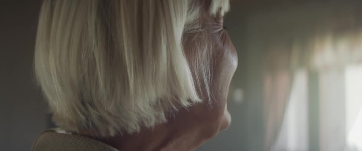 An elderly female caucasian standing in a house smiling and laughing