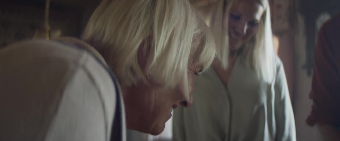 Three people in a room looking down and talking with a window in the background