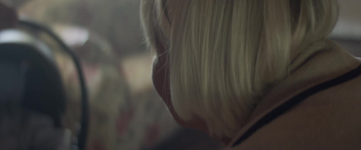 An elderly woman bends down and looks at her grandchild in a car seat that her daughter is holding