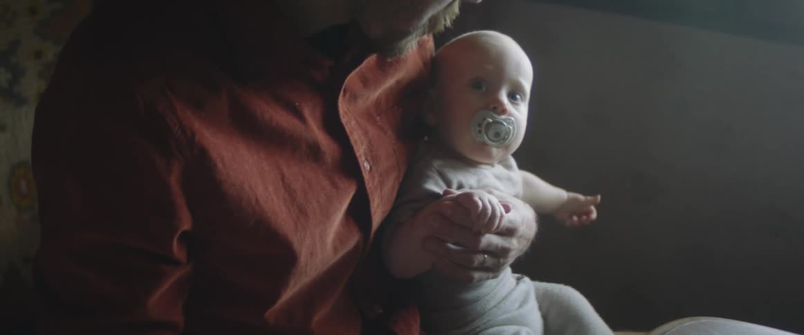 A man holds his son on his lap and rubs his hand