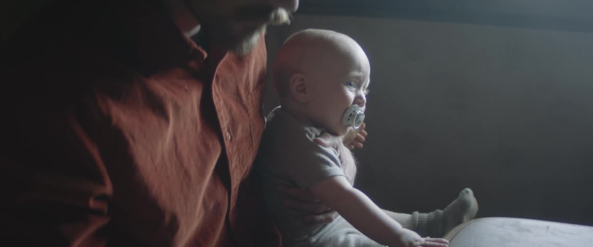 A man sitting by a table holding a baby