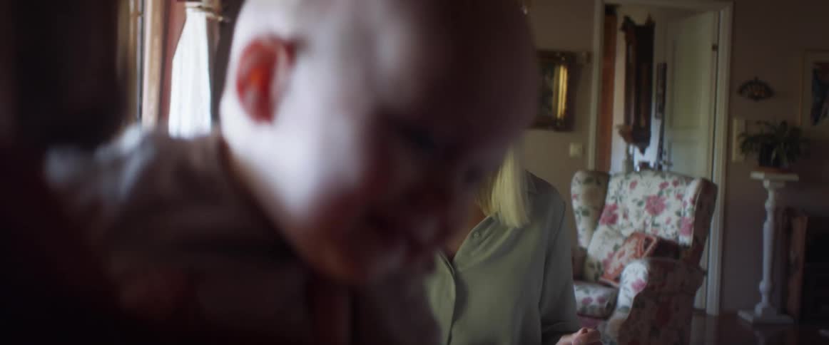 A woman smiles at her husband and infant son as they sit and eat dinner at home
