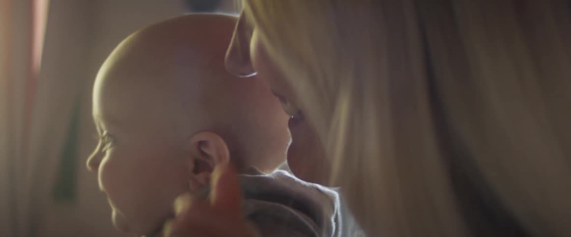 A woman smiles as she holds her son at home