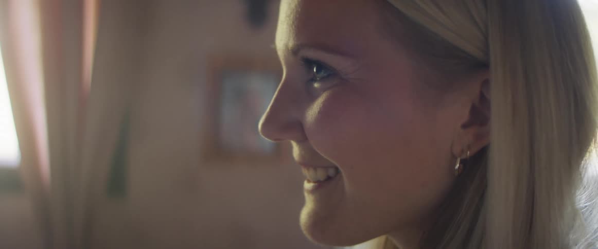 Side view of a smiling blonde woman with earrings