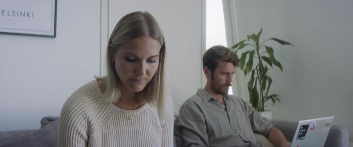 Young couple working from home sitting in a couch in the living room