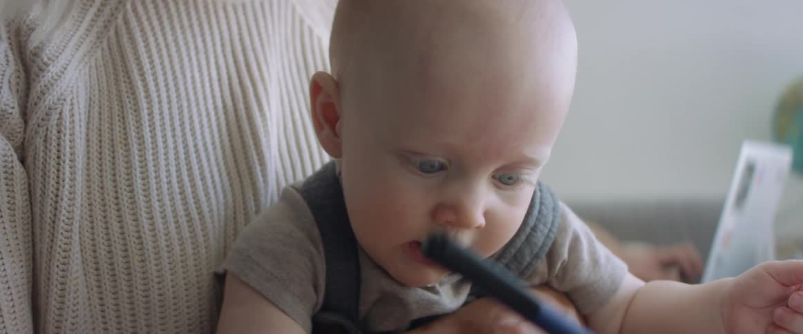 Close up of a babys face while sitting on his mothers lap at home