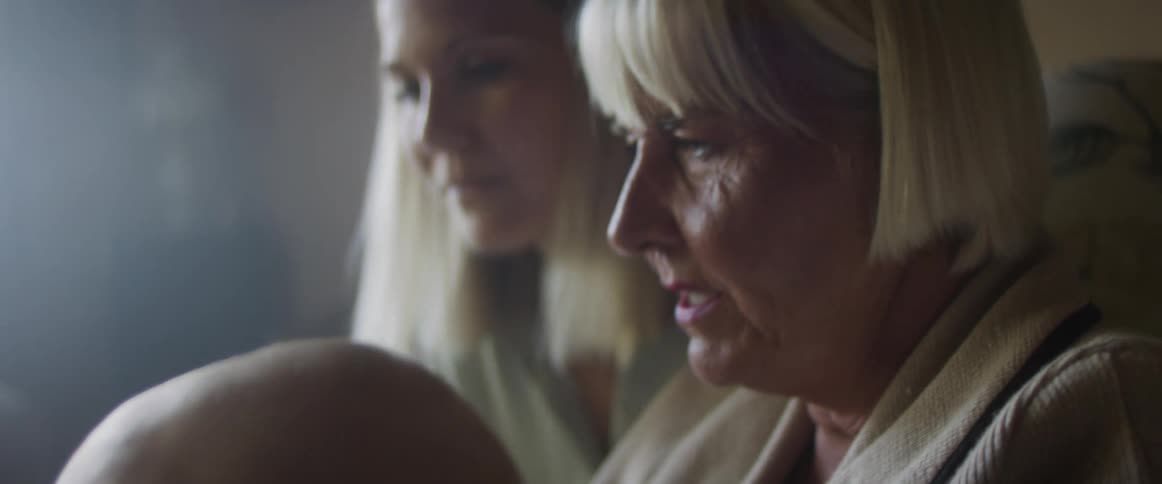 Grandmother shows pictures to her daughter and baby grandson on the couch in the livingroom