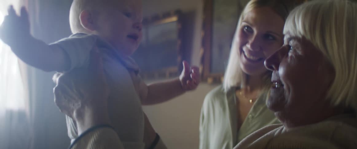 A grandmother bounces a baby on her lap with the mother sitting right beside them