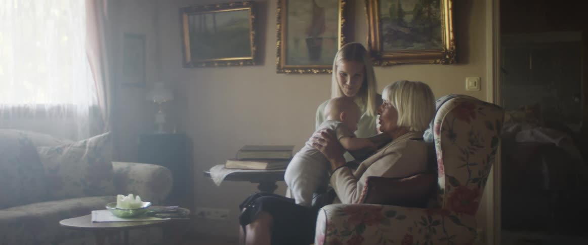 A grandmother holds an infant with the mother sitting next to them