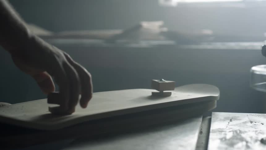 A person in a room turning a knob on a piece of wood on a workbench