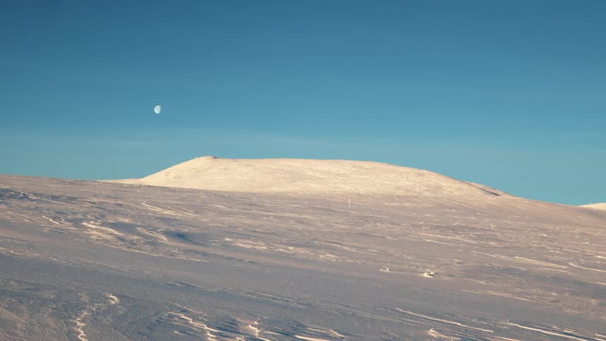 Snow and ice on the ground with the moon sky and clouds in the background