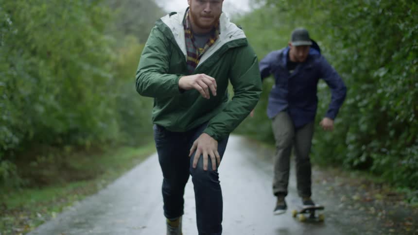 Two men are skateboarding in the rain