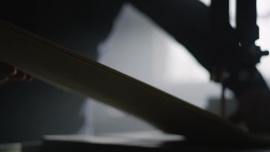 A man in a room using an electric saw to cut a piece of wood