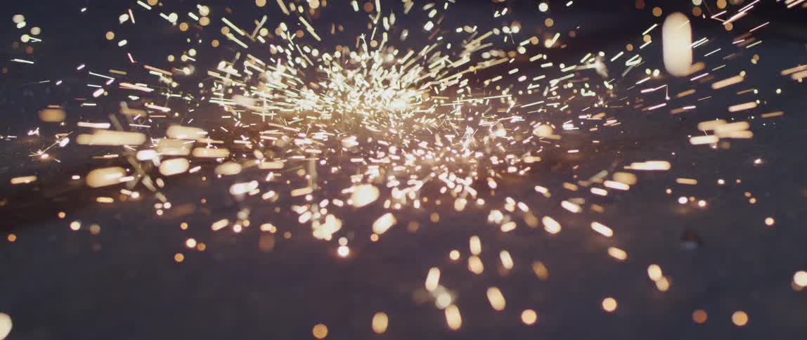Sparks shower down splattering against dark surface