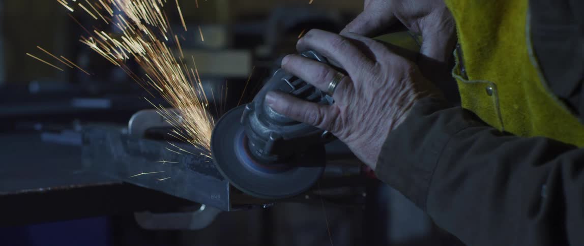 Sparks fly as a man in factory uses a tool
