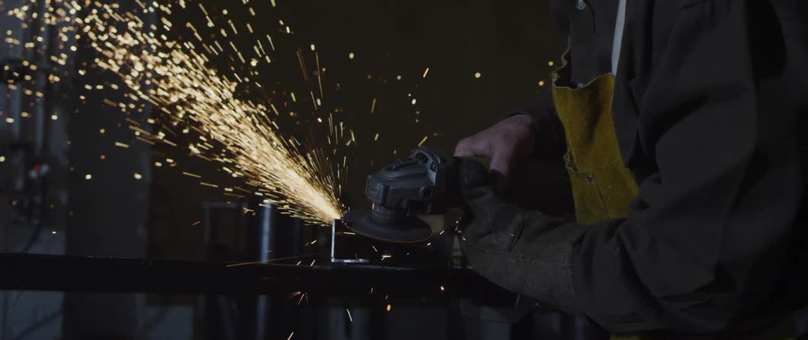 A worker is using an angle grinder on metal