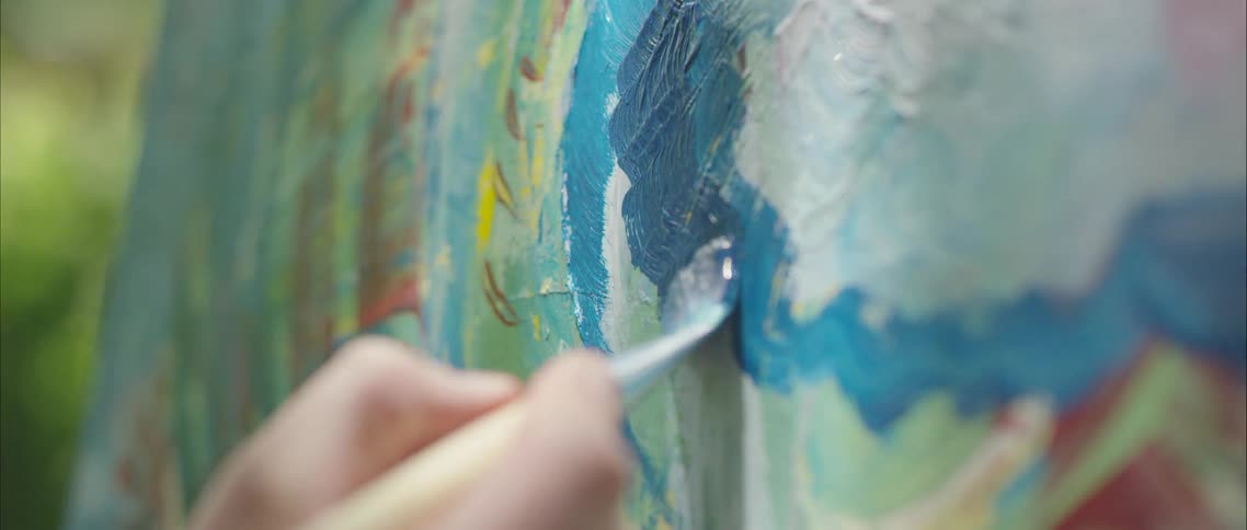 Painting on a canvas with blue oil paint outdoors
