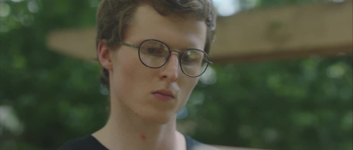 Young man wearing glasses painting on an easel outdoors