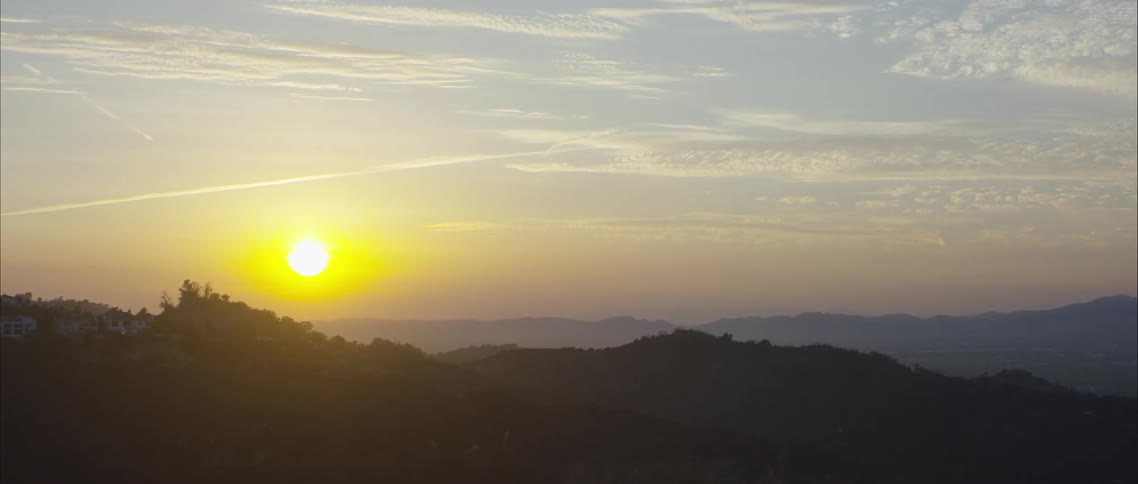Yellow sun hanging over the horizon over the mountains at sunset